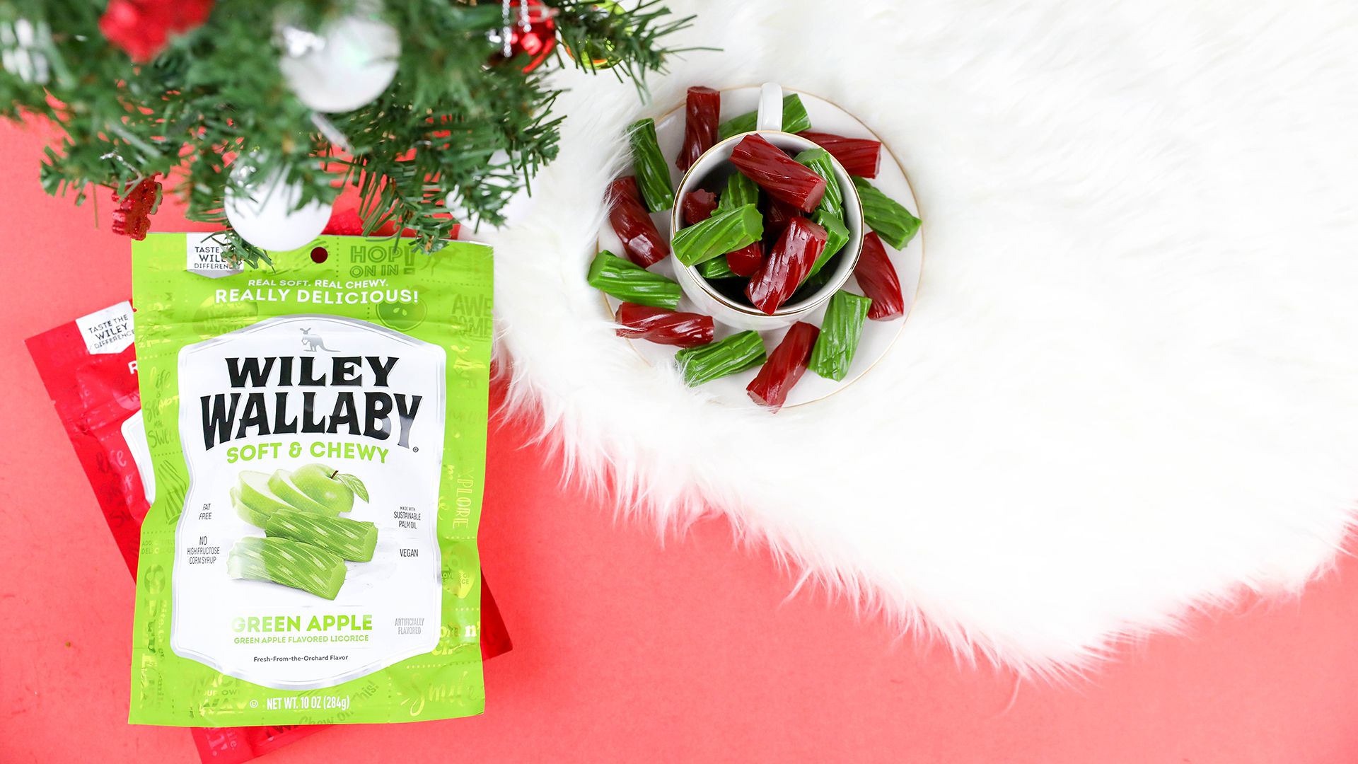 Wiley Wallaby Holiday Slide Wiley Wallaby Holiday Slide -- two bags of Wiley Wallaby, Classic Red and Green Apple displayed beside licorice pieces and Christmas tree